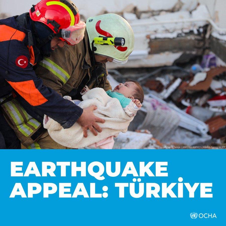 Photo of two rescue workers holding a baby.