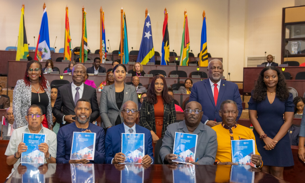 A group of people; some standing and some seated holding books in front of them.