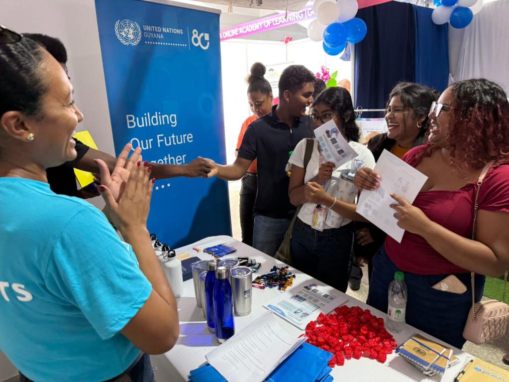 Persons at a booth speaking with each other. 