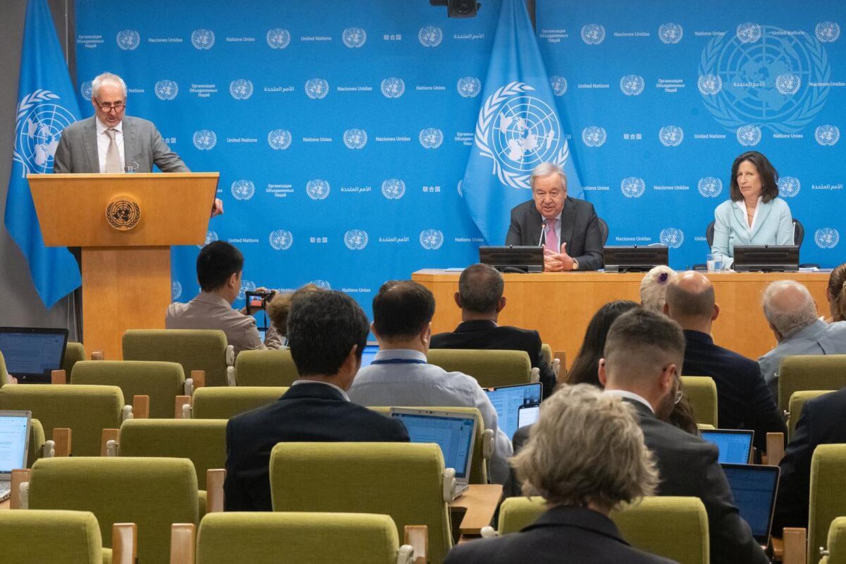 A man standing at a podium and a man and woman seated at a head table interacting with an audience.