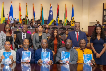 A group of people; some standing and some seated holding books in front of them.