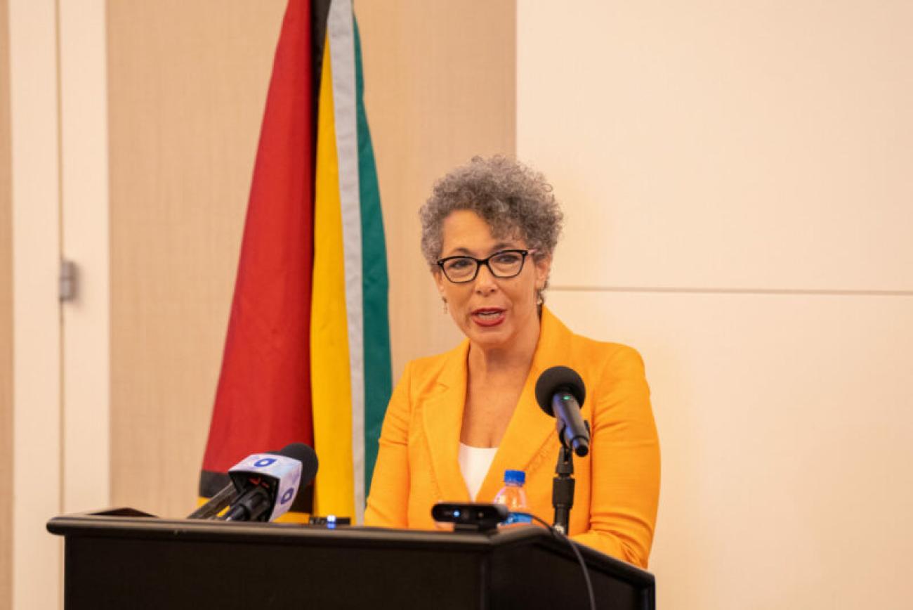 Woman standing in front a podium addressing an audience.