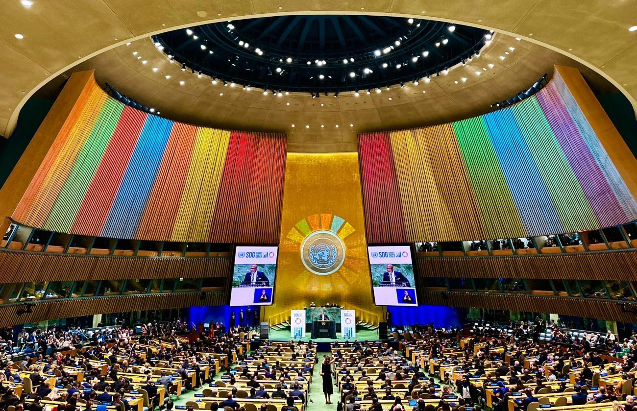 A room with a group of people seated and one person at a podium.