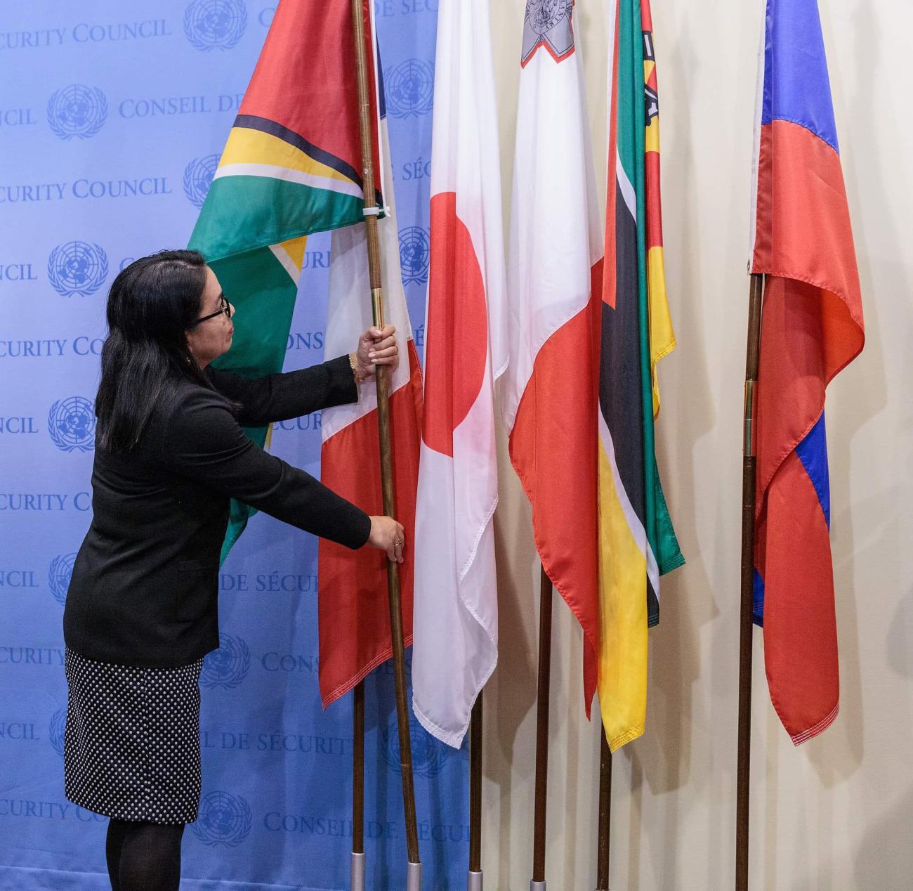 A woman placing a flag in a flag stand.