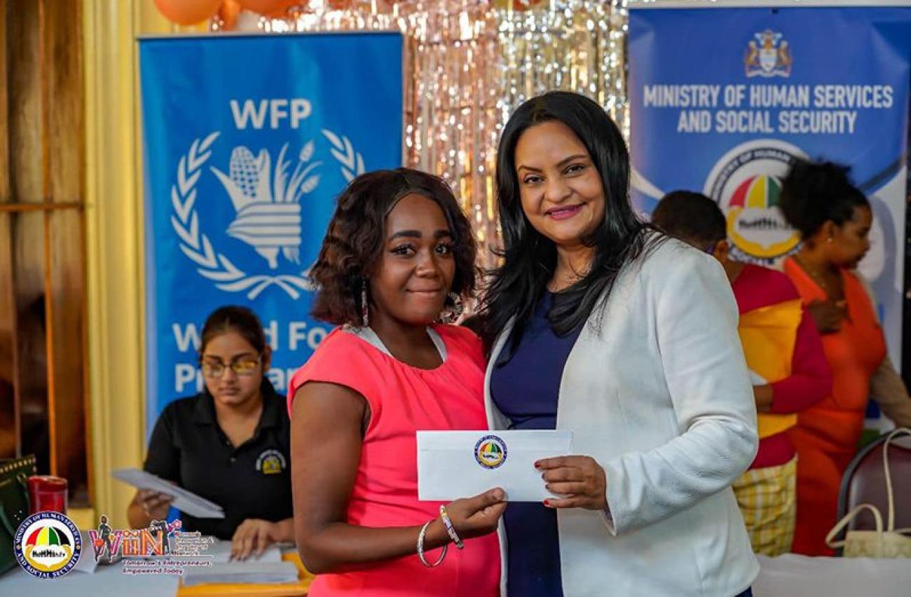 Two women standing holding an envelope.