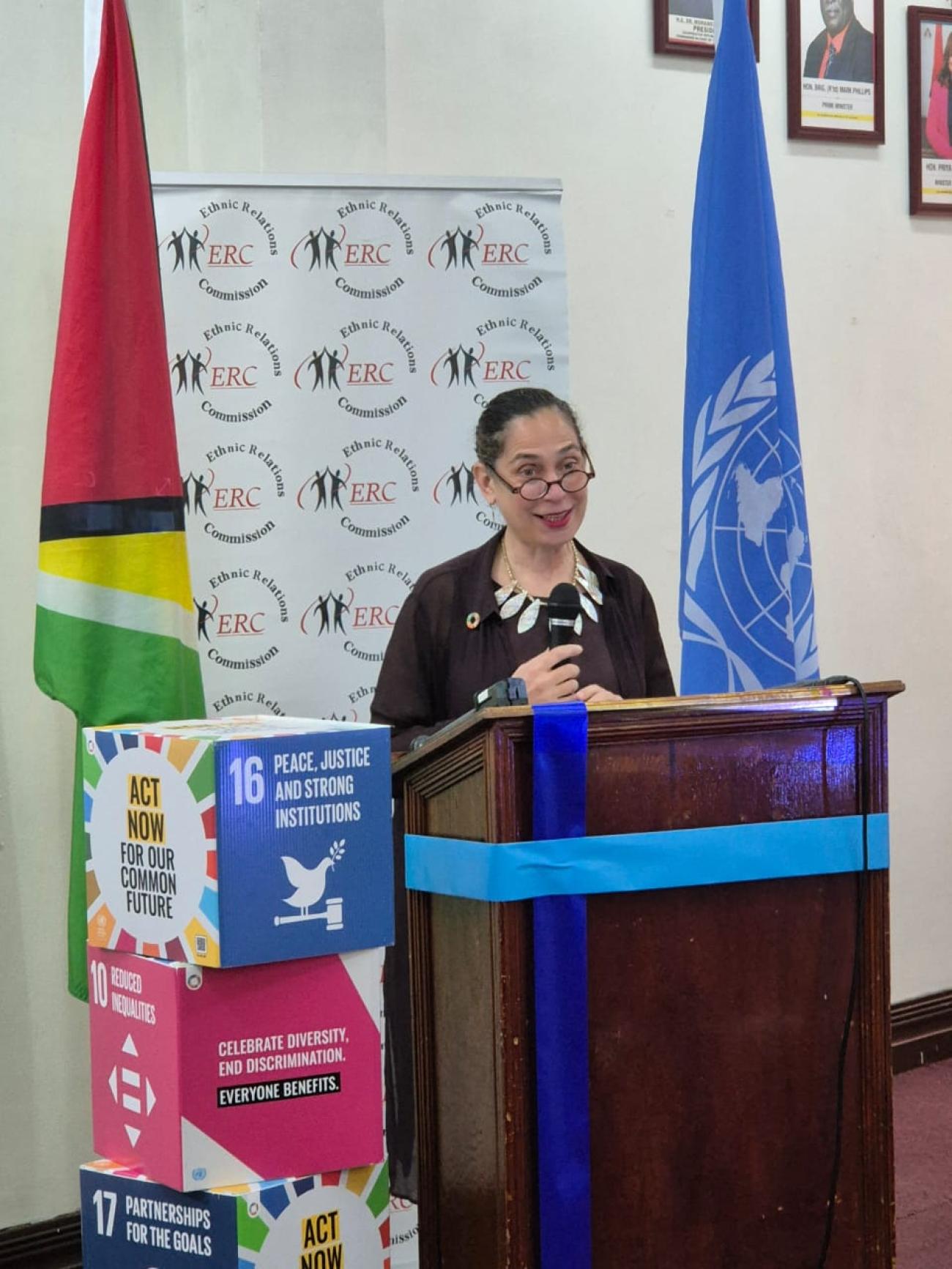 A woman standing in front of a microphone speaking at a podium.