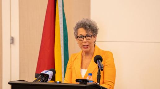 Woman standing in front a podium addressing an audience.