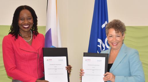 Two women standing holding up a signed document.
