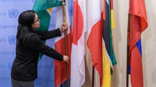 A woman placing a flag in a flag stand.
